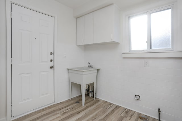 clothes washing area featuring cabinets, tile walls, and light wood-type flooring