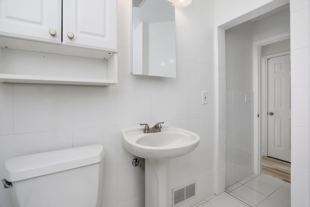 bathroom with tile patterned floors, toilet, and tile walls