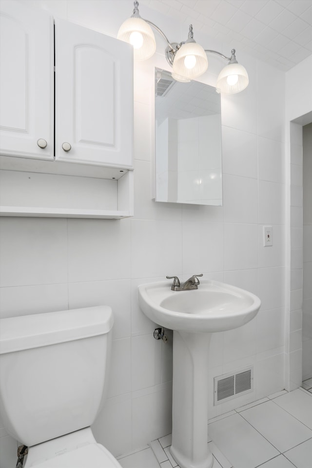 bathroom featuring tile patterned flooring, toilet, and tile walls