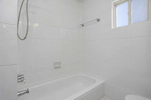 bathroom featuring toilet and tiled shower / bath