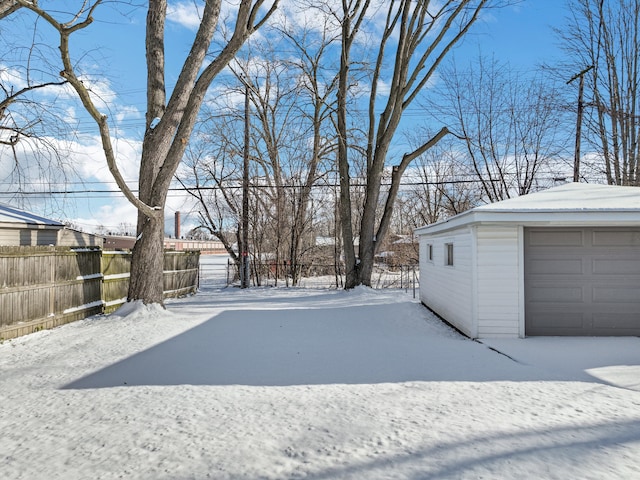 yard layered in snow featuring a garage and an outdoor structure