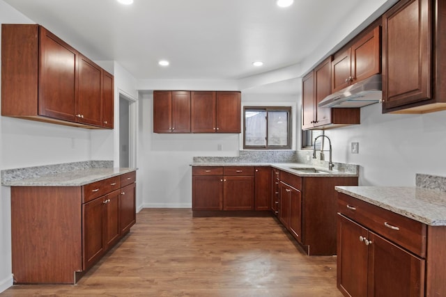 kitchen featuring light stone counters, sink, and light hardwood / wood-style floors