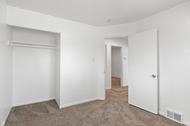 unfurnished bedroom featuring light carpet and a closet