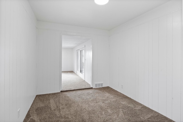 spare room featuring wooden walls and carpet floors