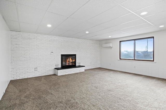 unfurnished living room featuring a fireplace, carpet floors, an AC wall unit, and brick wall