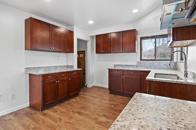 kitchen with hardwood / wood-style floors, light stone counters, and sink