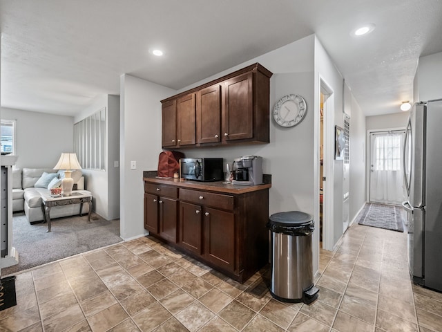 kitchen featuring dark brown cabinetry, light carpet, and appliances with stainless steel finishes