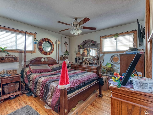 bedroom with a textured ceiling, light hardwood / wood-style floors, and ceiling fan