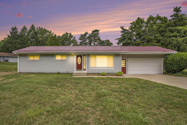 ranch-style home with a garage and a lawn