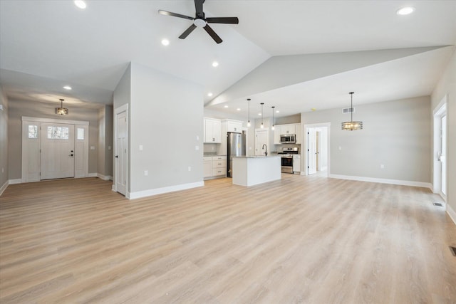 unfurnished living room with lofted ceiling, ceiling fan with notable chandelier, and light wood-type flooring