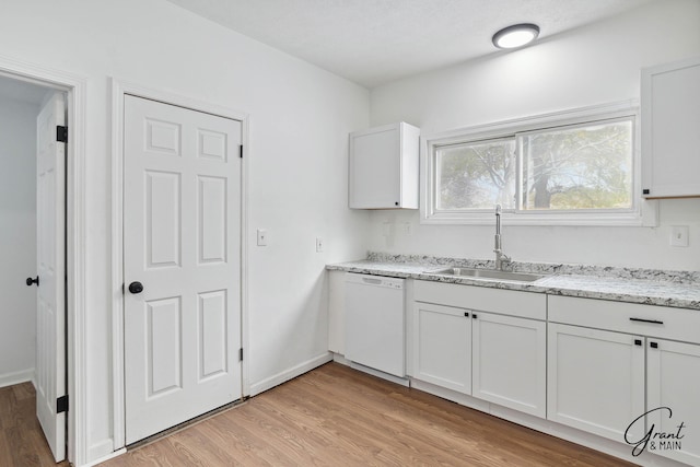 kitchen featuring white dishwasher, white cabinets, sink, light hardwood / wood-style flooring, and light stone countertops