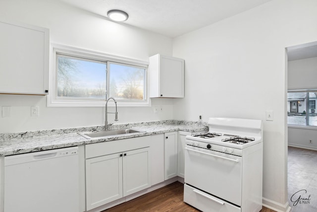 kitchen featuring white appliances, light stone counters, white cabinetry, and sink