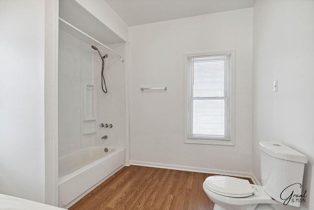 bathroom featuring hardwood / wood-style floors, toilet, and washtub / shower combination