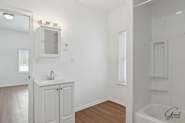 bathroom featuring hardwood / wood-style floors, plenty of natural light, washtub / shower combination, and vanity