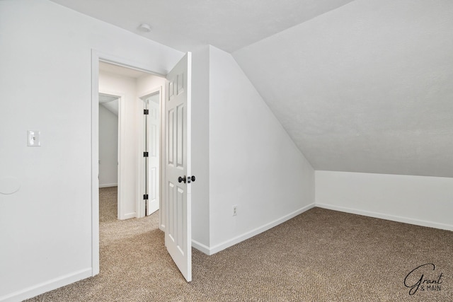 additional living space featuring light colored carpet and vaulted ceiling