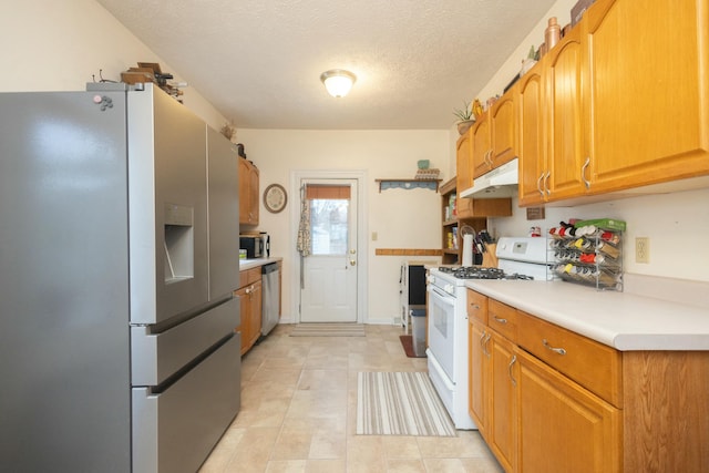 kitchen with light tile patterned floors, a textured ceiling, and appliances with stainless steel finishes