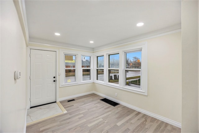 entryway featuring a healthy amount of sunlight, crown molding, and light hardwood / wood-style flooring