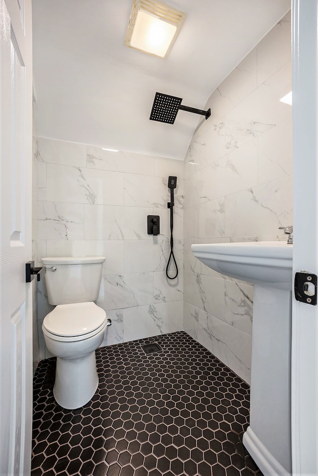 bathroom featuring toilet, tiled shower, and vaulted ceiling