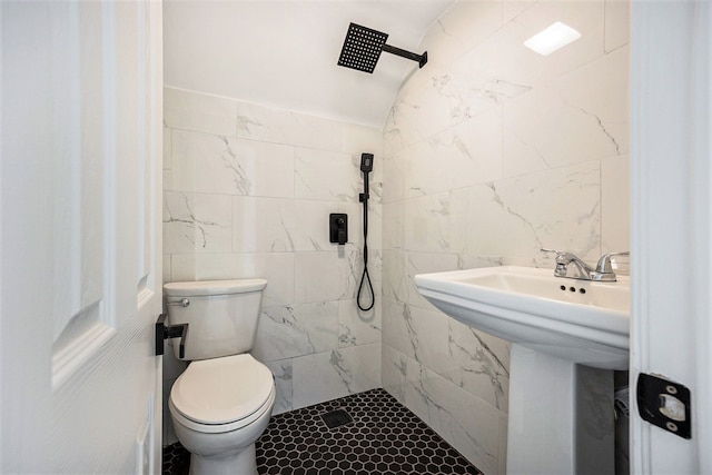 bathroom featuring tiled shower, tile walls, and toilet