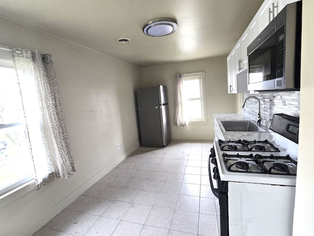 kitchen featuring light tile patterned flooring, sink, white cabinetry, stainless steel appliances, and backsplash