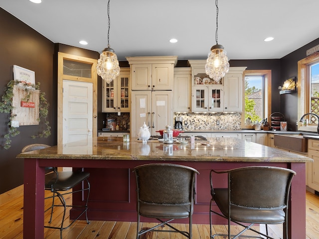 kitchen with cream cabinets, a spacious island, and light hardwood / wood-style flooring