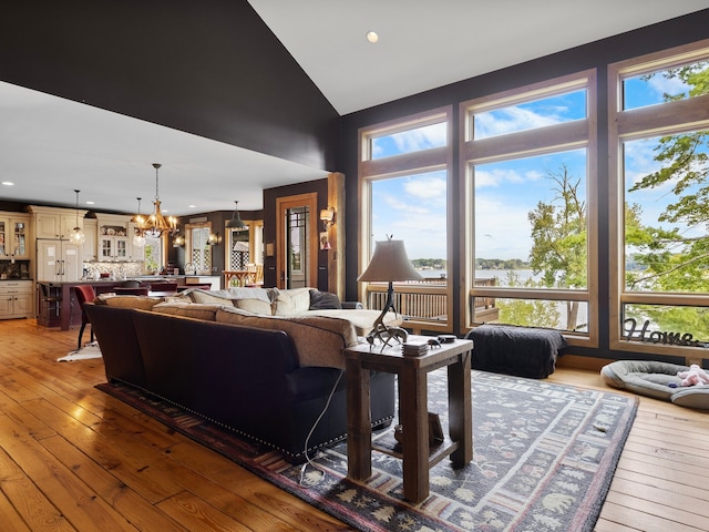 living room featuring wood-type flooring, high vaulted ceiling, and an inviting chandelier