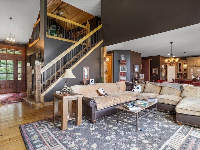 living room with wood-type flooring, ceiling fan with notable chandelier, and high vaulted ceiling