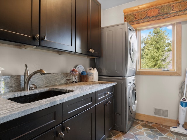 laundry room with sink, cabinets, and stacked washer / dryer