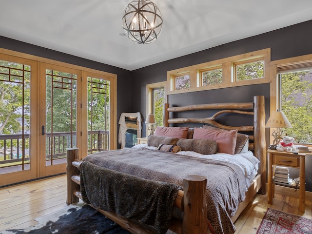 bedroom with french doors, an inviting chandelier, access to outside, and light hardwood / wood-style flooring