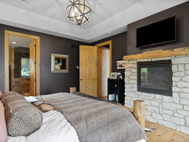 bedroom featuring a chandelier, a fireplace, and wood-type flooring