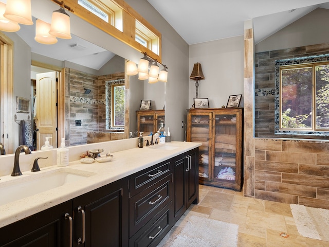 bathroom featuring vanity, a tile shower, and vaulted ceiling