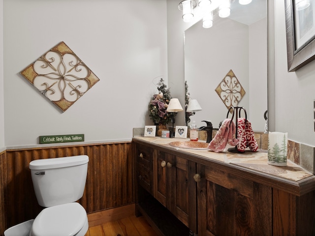 bathroom with wooden walls, hardwood / wood-style floors, vanity, and toilet