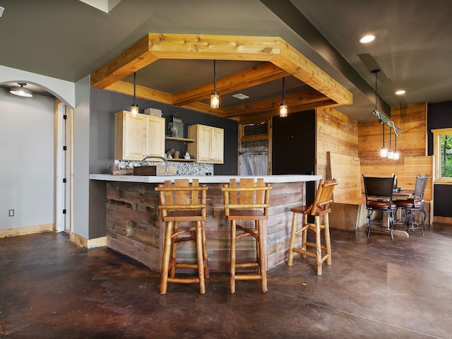 bar with tasteful backsplash, beamed ceiling, pendant lighting, wooden walls, and light brown cabinetry