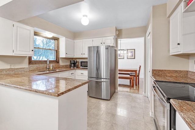 kitchen with sink, light stone counters, kitchen peninsula, white cabinets, and appliances with stainless steel finishes