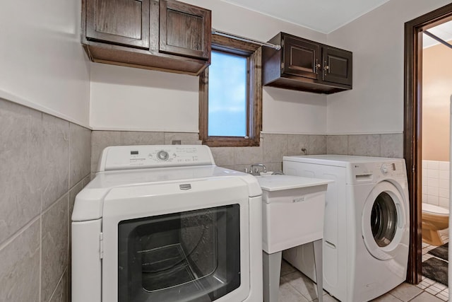 laundry area with cabinets, separate washer and dryer, tile walls, and a healthy amount of sunlight