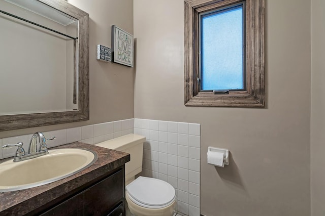 bathroom with vanity, toilet, and tile walls