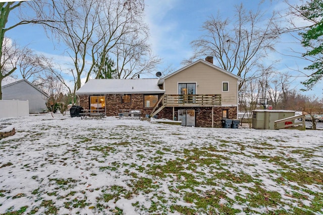 snow covered property featuring a deck and a storage shed