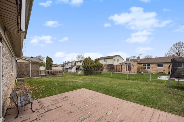 wooden terrace with a gazebo, a lawn, and a trampoline