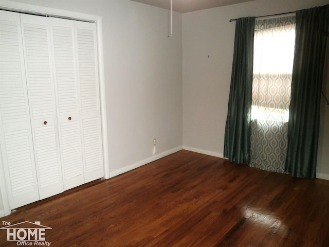 unfurnished bedroom with dark hardwood / wood-style flooring and a closet