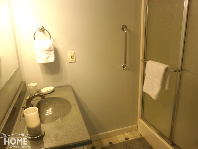 bathroom featuring tile patterned flooring, a shower with shower door, and sink