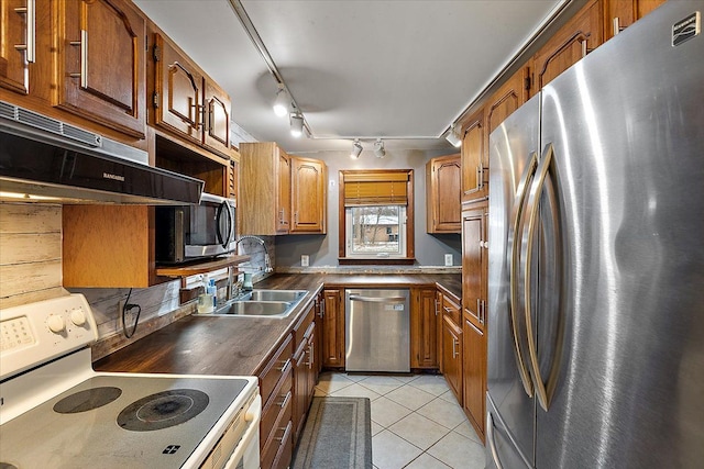 kitchen featuring sink, light tile patterned flooring, range hood, and appliances with stainless steel finishes