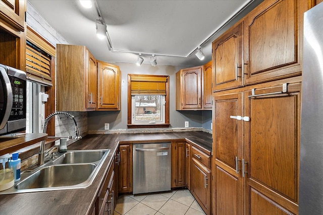 kitchen featuring dishwasher, rail lighting, light tile patterned flooring, and sink