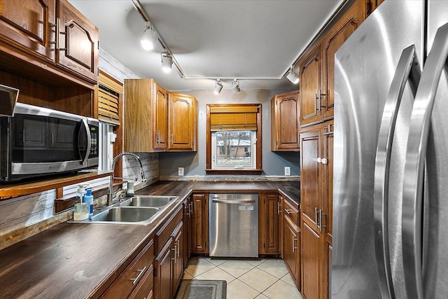 kitchen with sink, rail lighting, stainless steel appliances, decorative backsplash, and light tile patterned floors