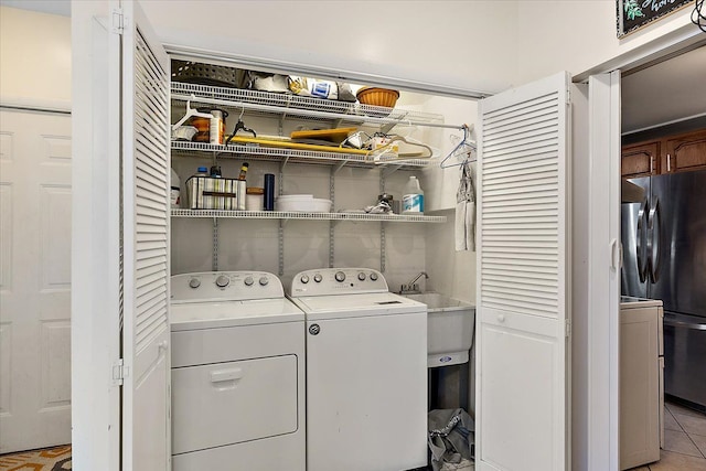 laundry area featuring separate washer and dryer, sink, and light tile patterned floors