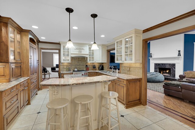 kitchen featuring a center island, sink, stainless steel stove, a fireplace, and decorative light fixtures