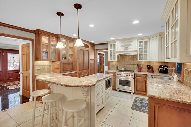 kitchen with appliances with stainless steel finishes, ornamental molding, a breakfast bar, sink, and decorative light fixtures