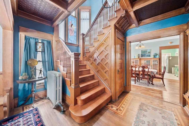 stairway featuring radiator heating unit, beamed ceiling, wood-type flooring, and coffered ceiling