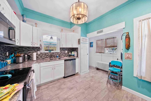 kitchen featuring sink, radiator heating unit, crown molding, white cabinets, and appliances with stainless steel finishes