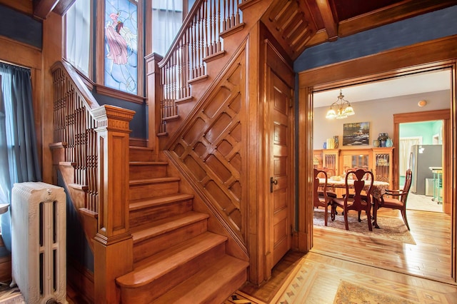 staircase with beam ceiling, crown molding, a chandelier, and hardwood / wood-style flooring