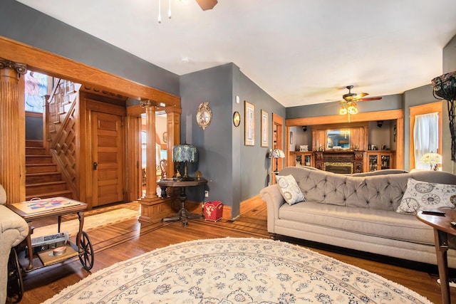 living room featuring ornate columns, ceiling fan, and wood-type flooring